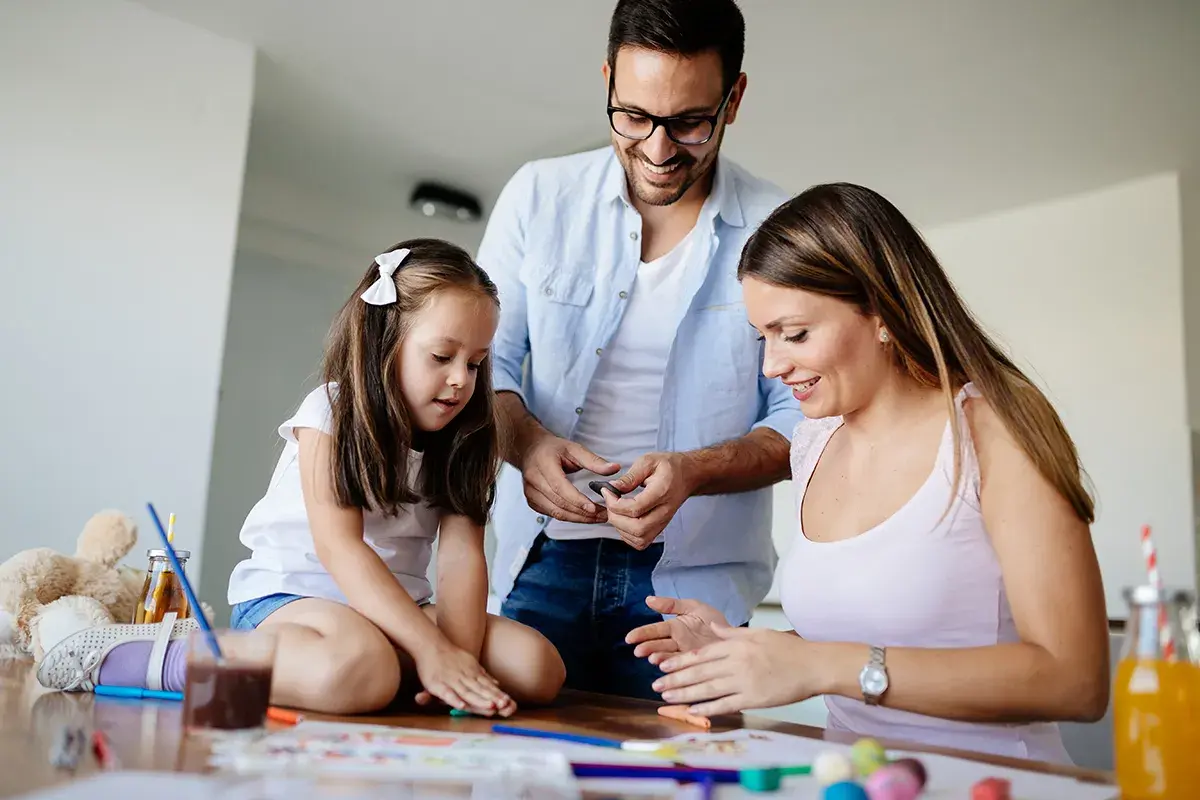 Familia feliz disfrutando de una **actividad día de la familia**, creando arte con plastilina y colores.