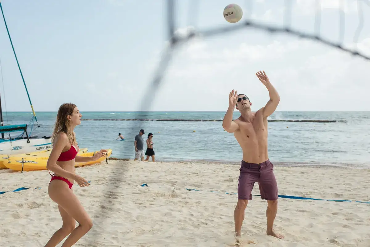 J&oacute;venes disfrutan de juegos en la playa, jugando voleibol bajo el sol.