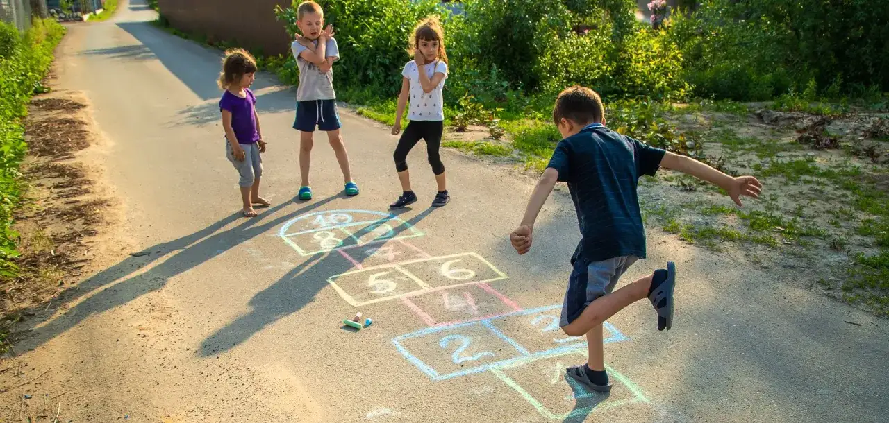Ni&ntilde;os jugando a la rayuela en la calle, un cl&aacute;sico de los juegos de patio.