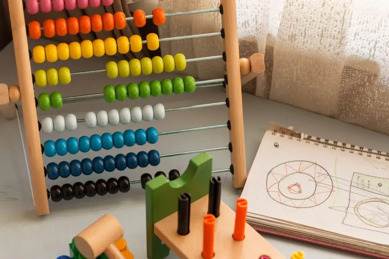 &Aacute;baco de madera con cuentas de colores y un cuaderno con dibujos, ideales para ejercicios de atenci&oacute;n y aprendizaje temprano.