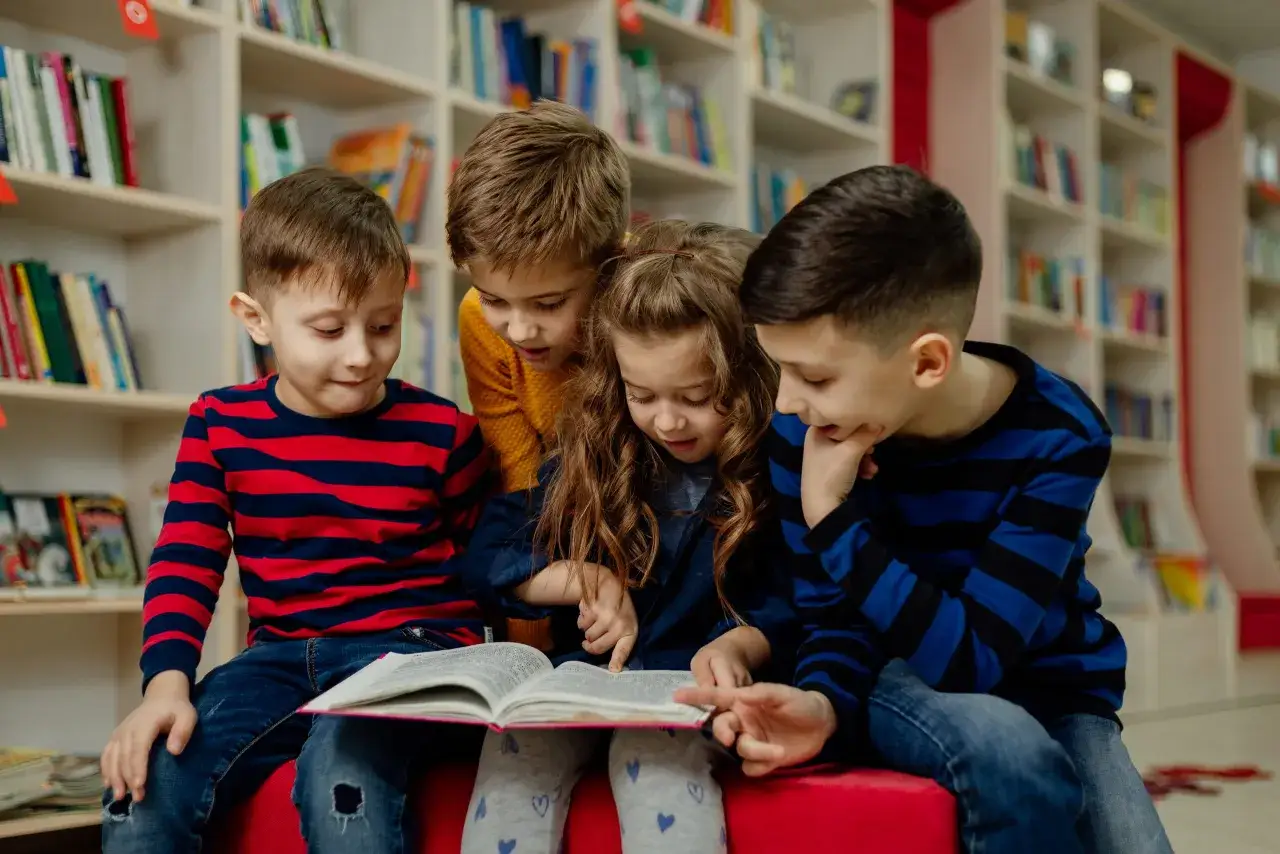 Niños concentrados en un libro, aprendiendo sobre velocidad lectora primaria.