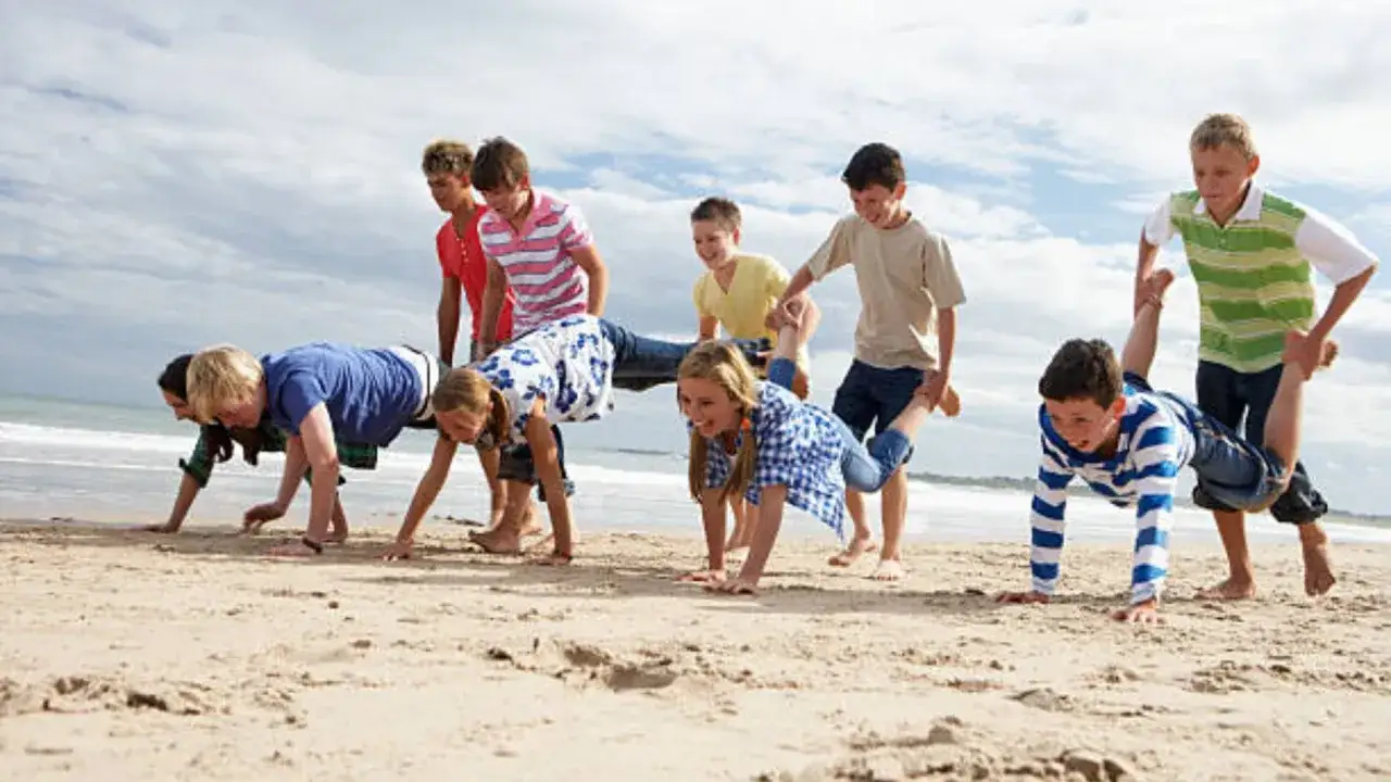 Ni&ntilde;os jugando a la carretilla en la playa. &iexcl;Una idea genial que hacer en vacaciones con ni&ntilde;os para divertirse al aire libre!